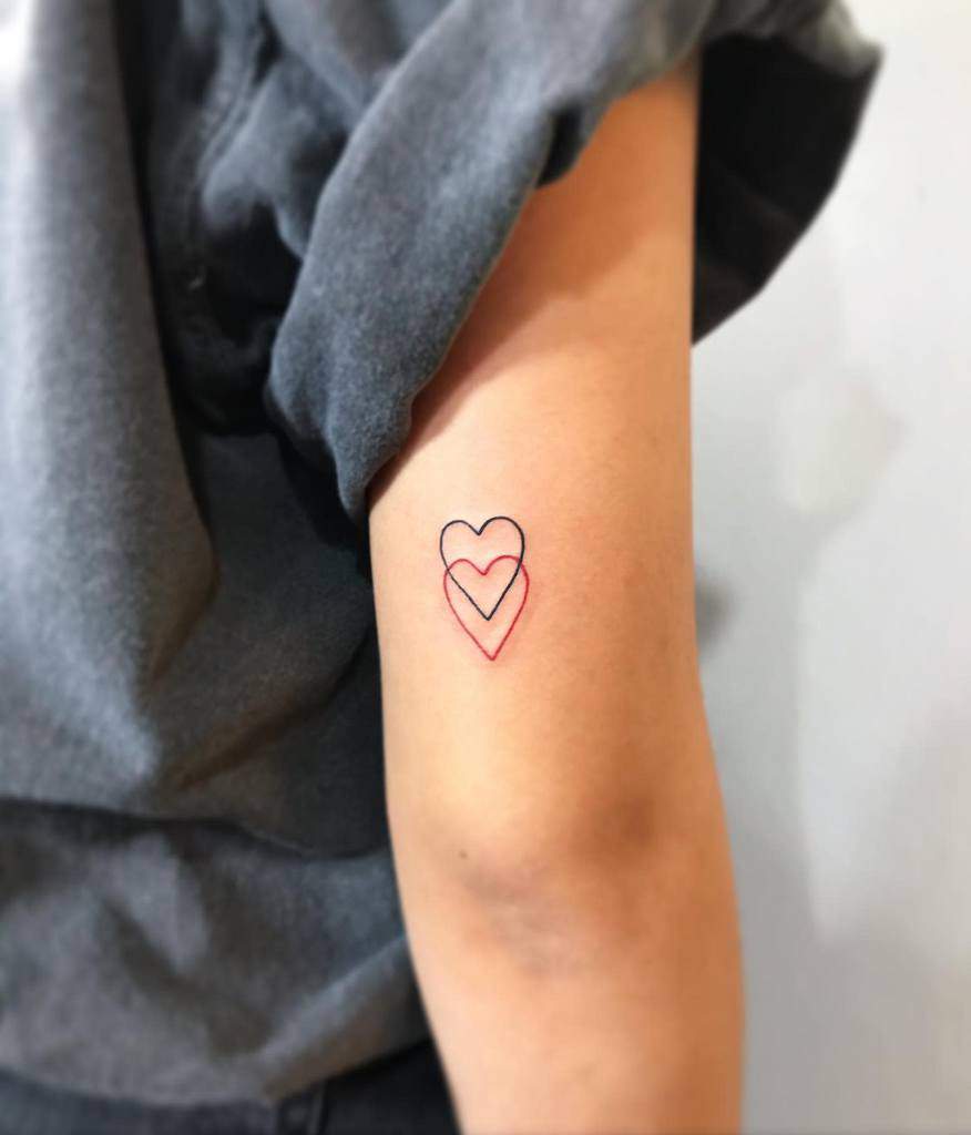 Tattoo of two overlapping hearts outlined in red and black on an upper arm
