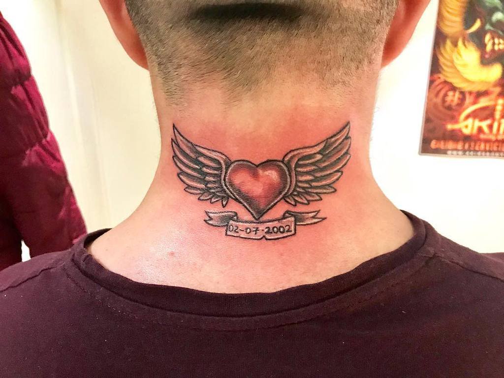 Tattoo of a heart with wings, adorned with a date banner, on the back of a person's neck