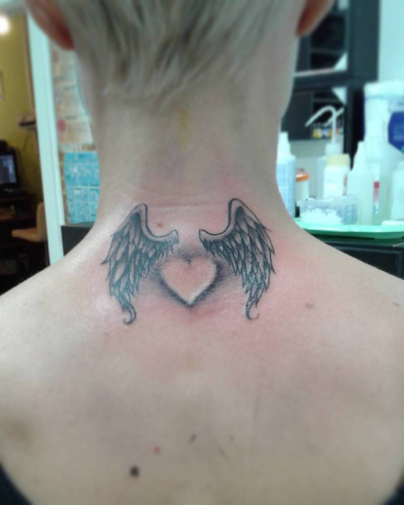 Tattoo of heart-shaped wings on the back of a person's neck