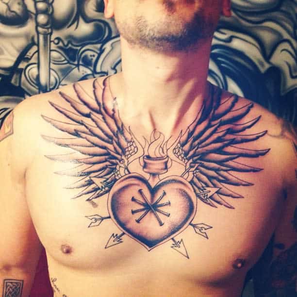 Tattoo of a winged heart, complete with flames and arrows decorating the vibrant design