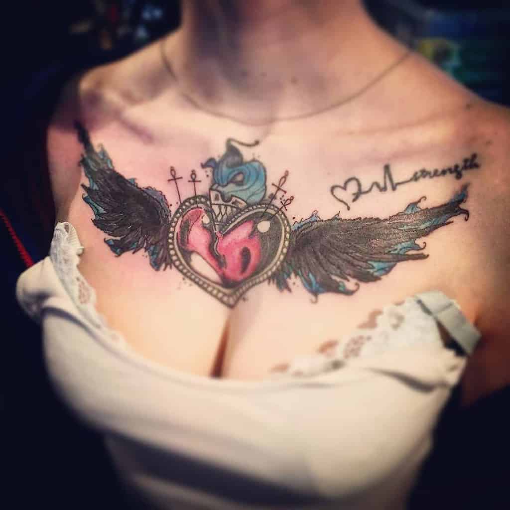 A colorful heart adorned with delicate wings graces a woman's chest, peeking out from above her white top
