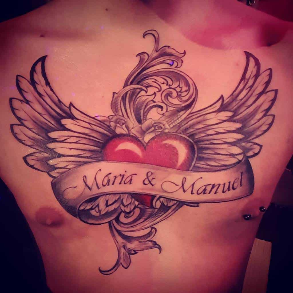 Tattoo of two hearts with wings and the names "Maria & Manuel" gracefully inked on a person's chest