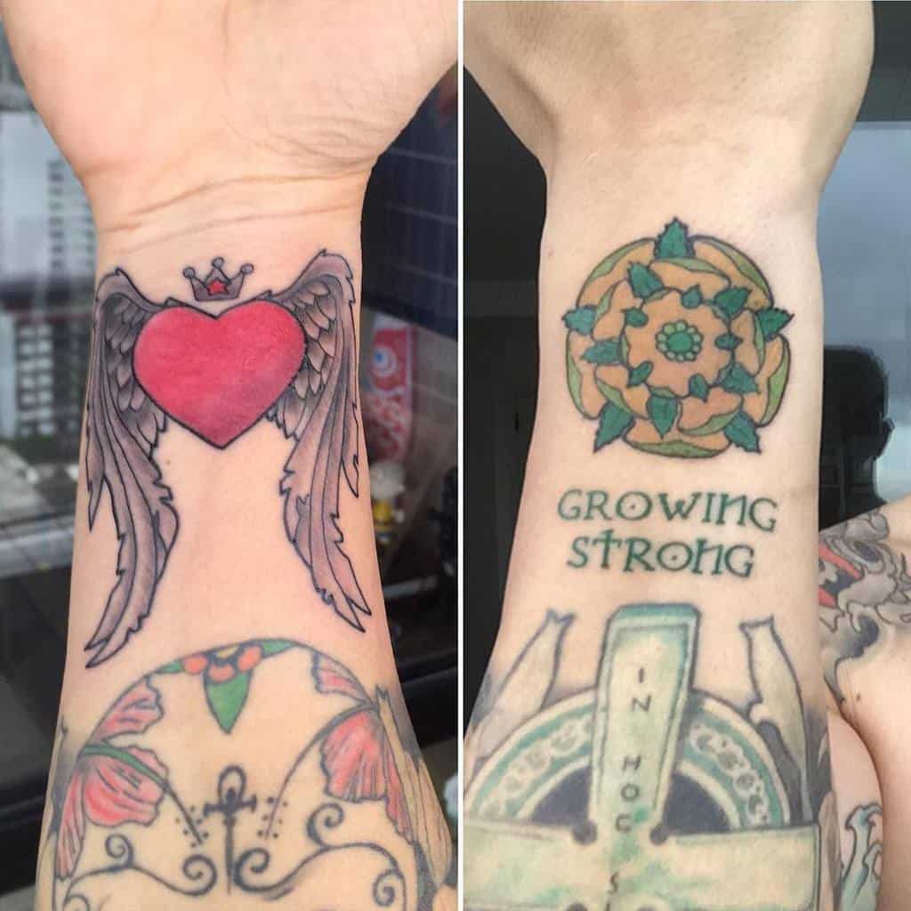 Tattoo of a heart with wings on left wrist, flower design with "Growing Strong" text on right wrist