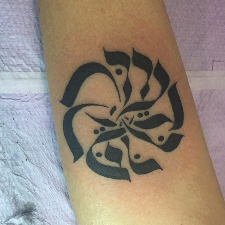 Black floral-like calligraphic tattoo on forearm