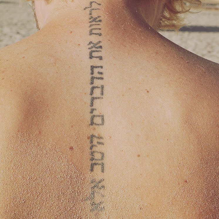 Tattoo with a vertical Hebrew script along a spine