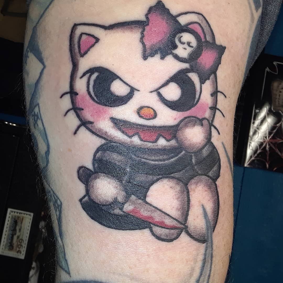 Tattoo of a menacing Hello Kitty holding a bloody knife with a skull bow on its head