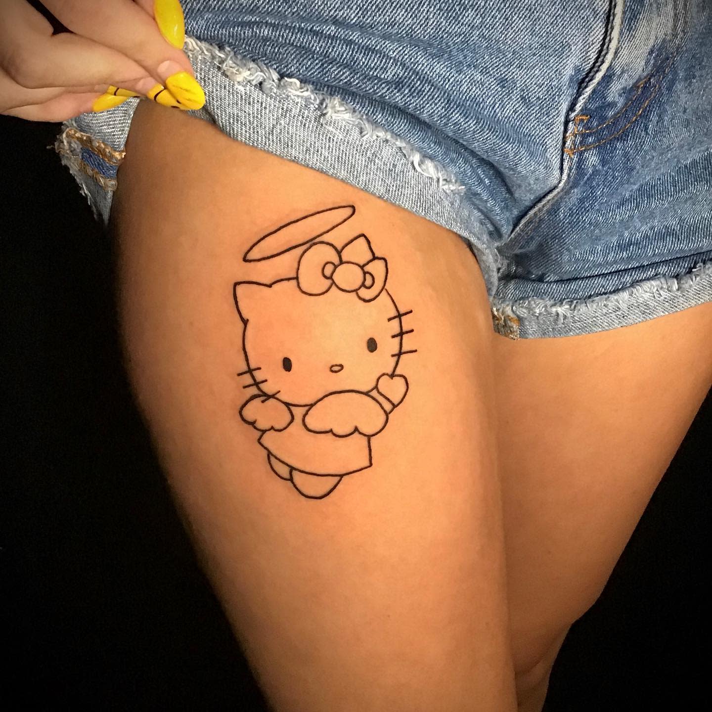 A simple tattoo of a Hello Kitty angel on an upper thigh
