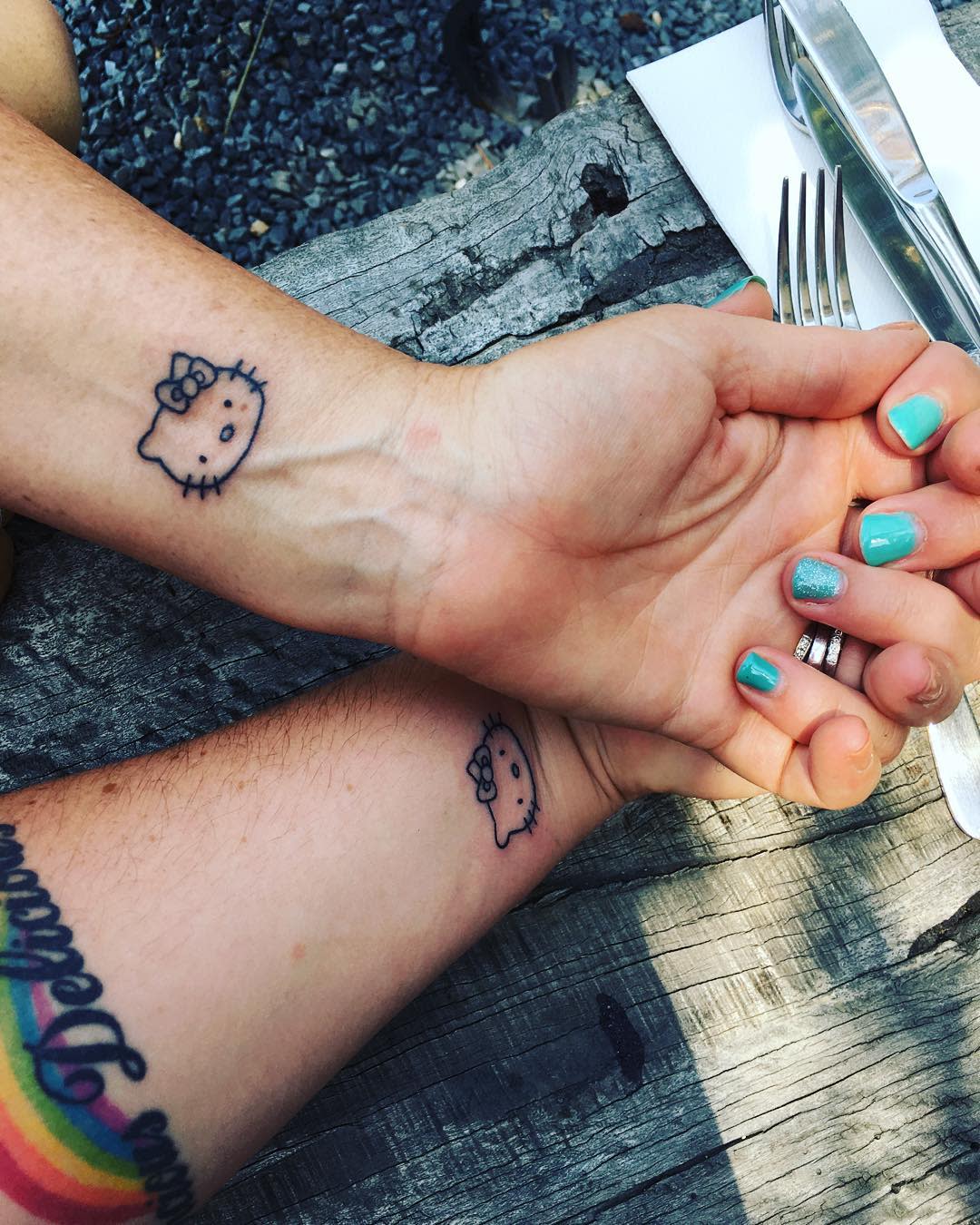 Two hands with Hello Kitty tattoos on their wrists