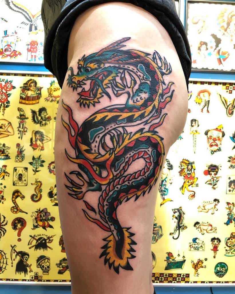 Tattoo of a colorful dragon with flames on a woman's hip and thigh