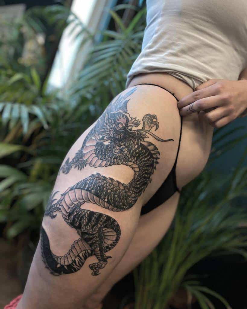 Woman showing a detailed dragon tattoo on her thigh