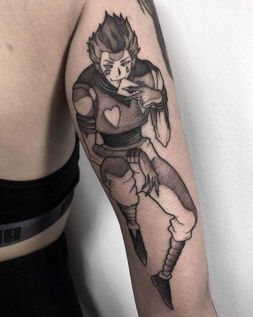 Black-and-white Hisoka Morow tattoo from Hunter X Hunter, featuring intricate shading, dynamic pose, and his signature playing card