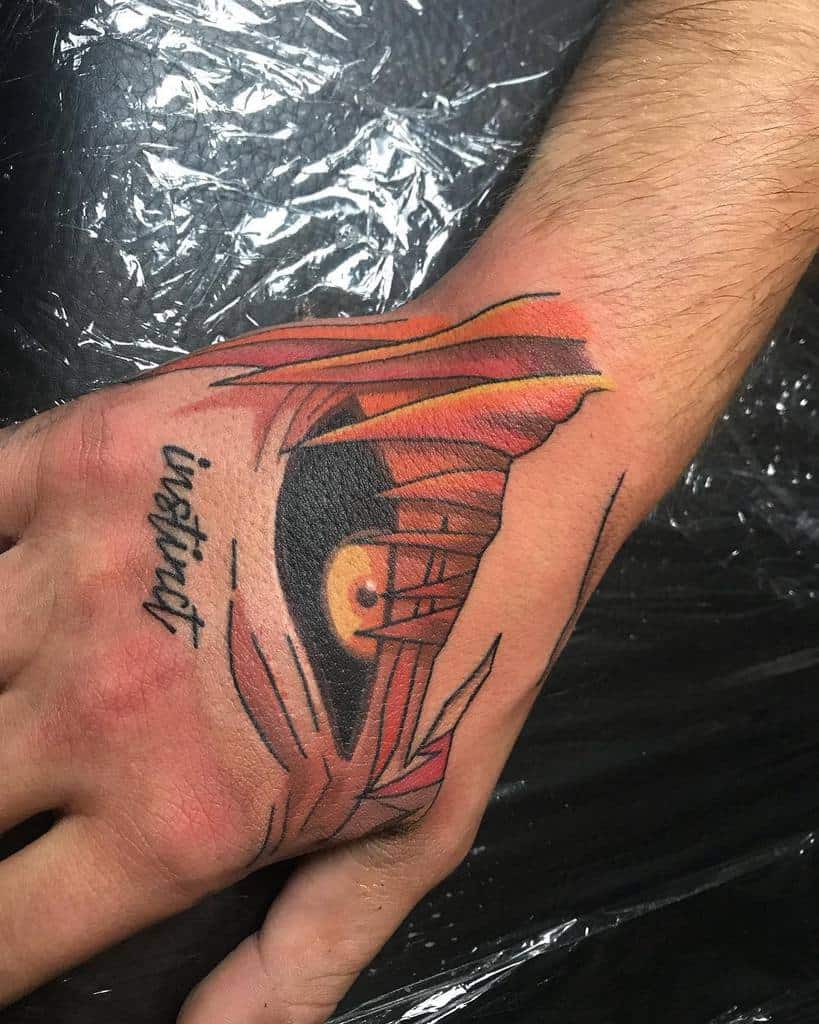 Colorful tattoo of Hollow Ichigo’s eye from Bleach, with sharp red and orange shading, featuring the word 'instinct' in script