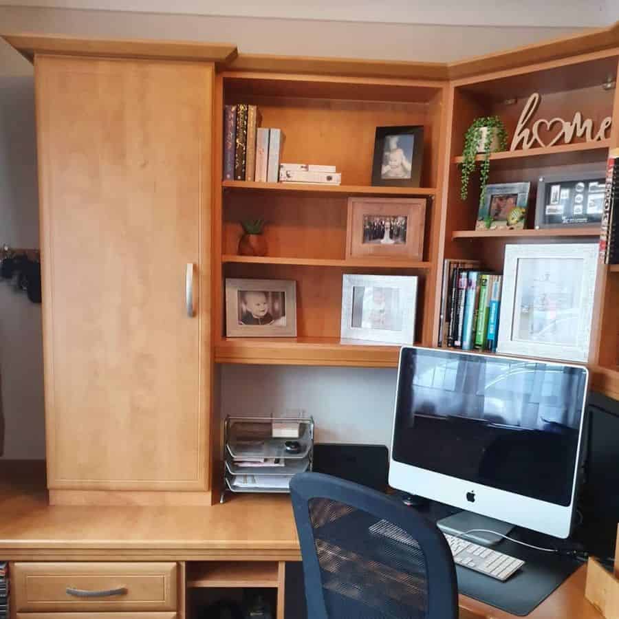 Home office desk with a computer, books, and framed photos on wooden shelves