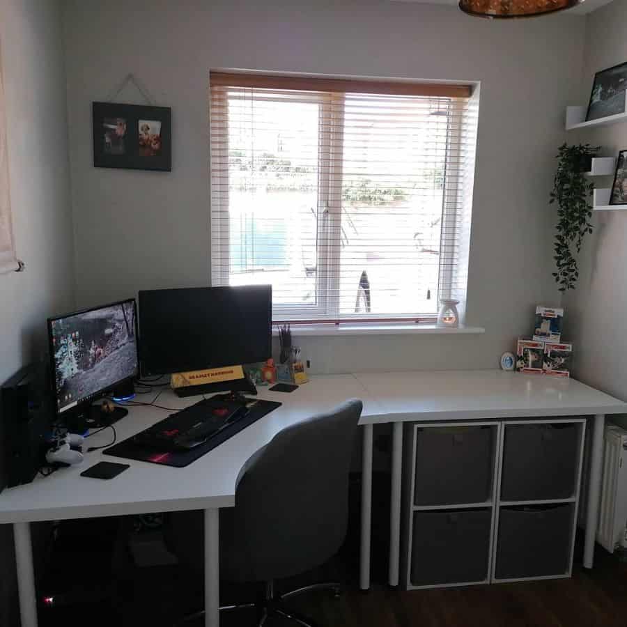 Home office with a desk, dual monitors, chair, indoor plant, and a window with blinds