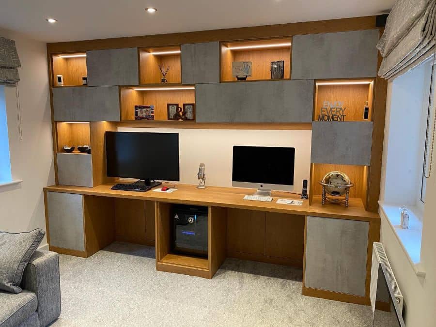 Modern home office with dual monitors, shelving, and decorative items, featuring cozy lighting and minimalist design