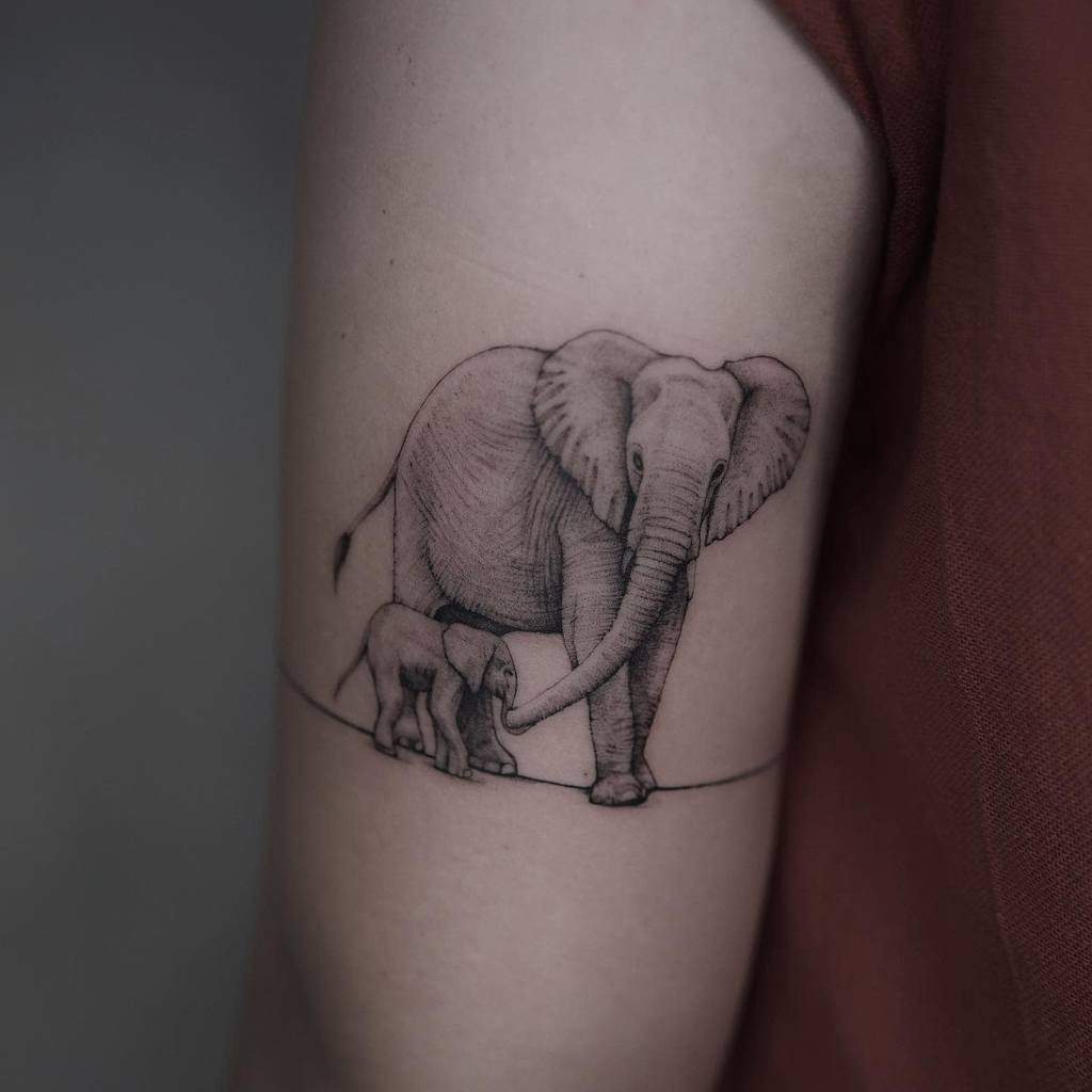 Tattoo of a large elephant and a baby elephant on someone's upper arm intricately crafted using single needle technique