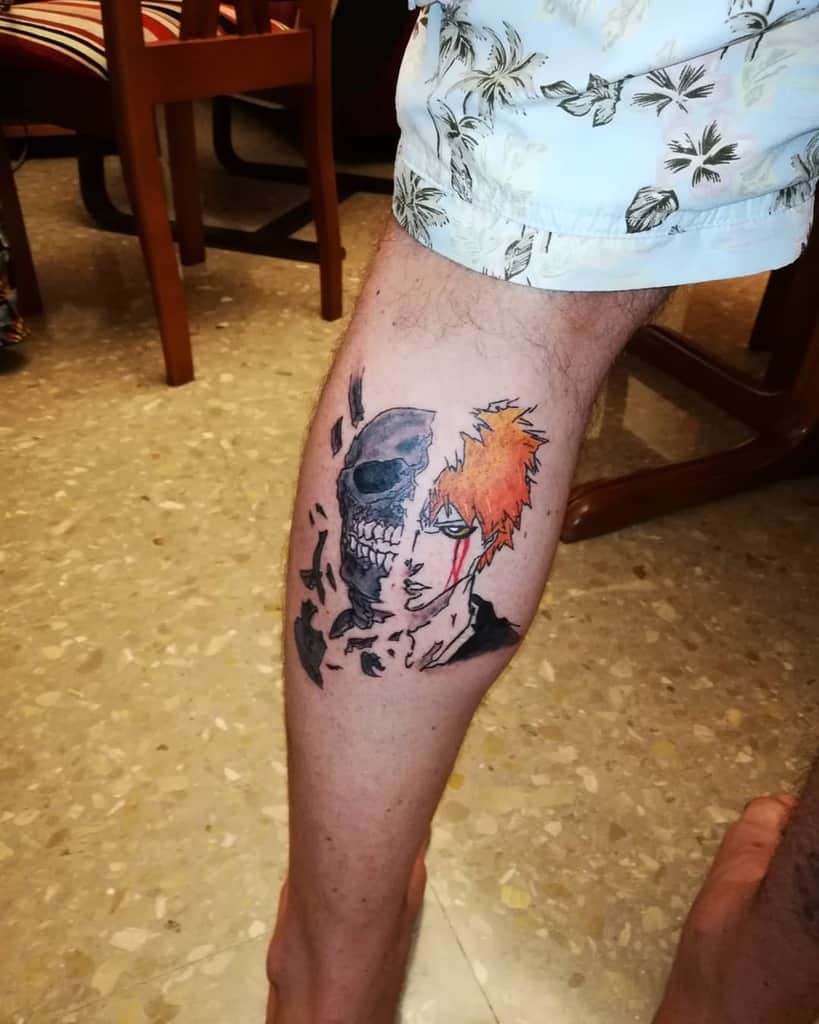 Colorful tattoo of Ichigo Kurosaki from Bleach, featuring a half-Hollow skull design with cracked fragments and intense green eyes 