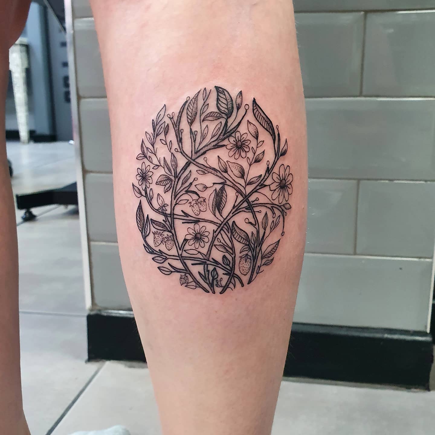 Forearm tattoo featuring an intricate floral design in the shape of an oval