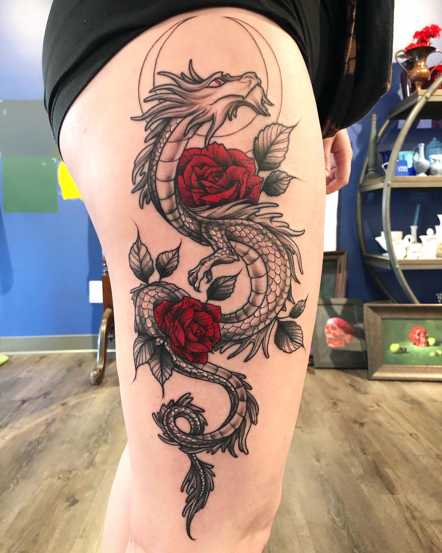 Dragon and red roses tattoo on a thigh
