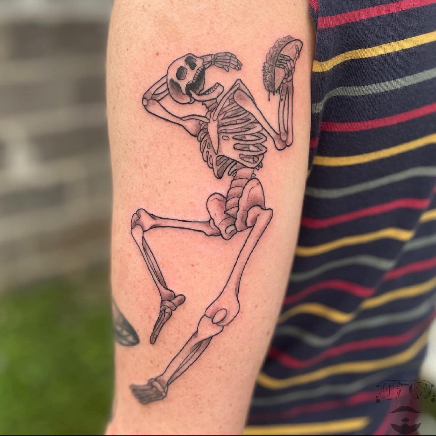 Tattoo of a dancing skeleton on an upper arm