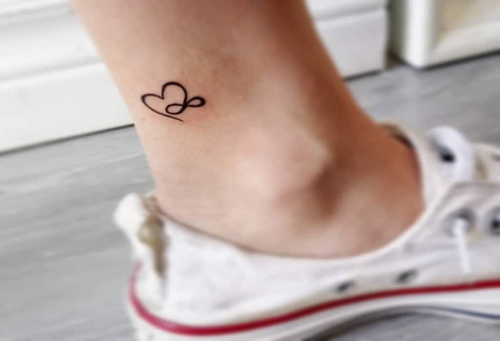 Simple heart tattoo with an infinity symbol intertwined on the ankle