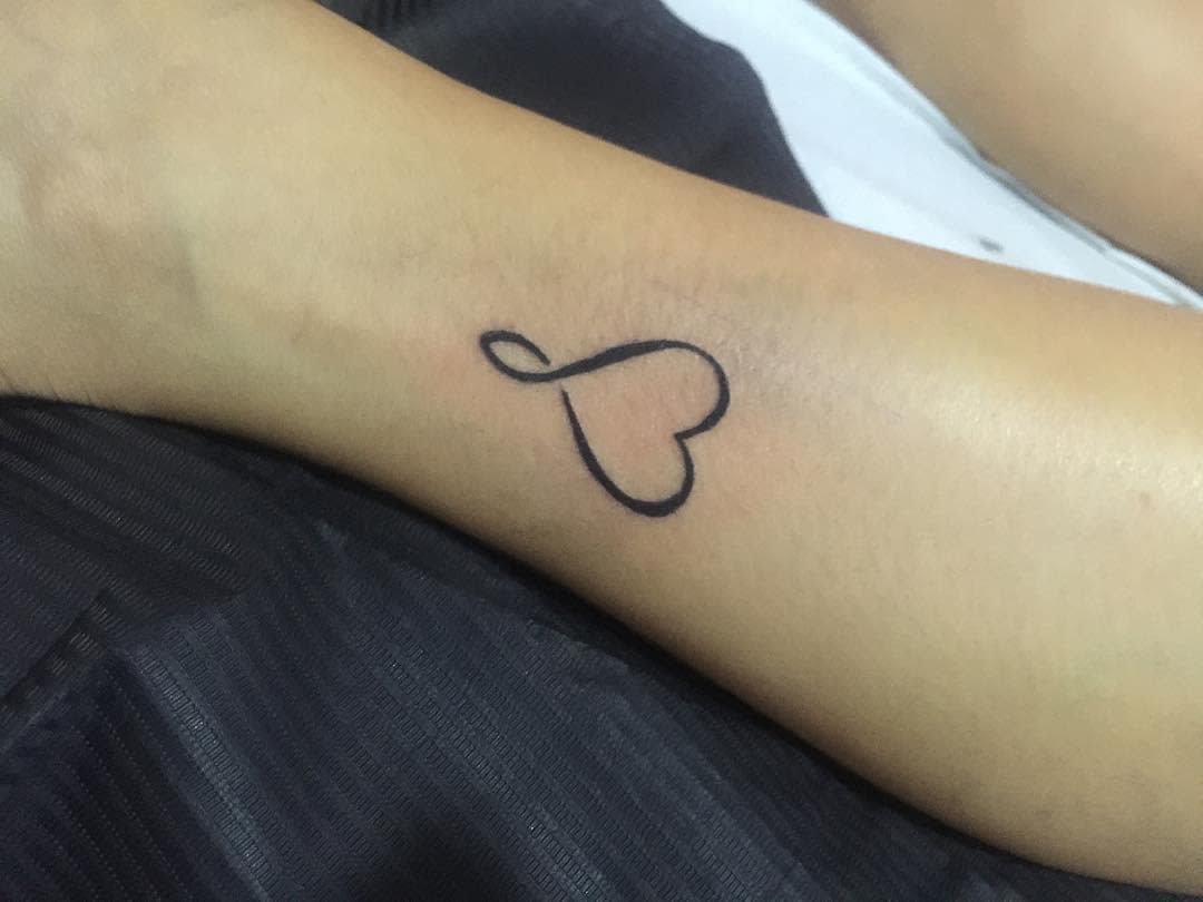 Outline of a heart-shaped tattoo intertwined with an infinity symbol on a lower leg