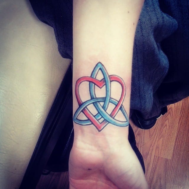 A colorful Celtic knot tattoo with heart elements and an infinity symbol gracefully entwines a wrist