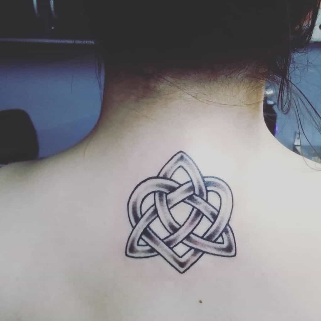 A tri-loop Celtic knot tattoo, intricately designed to resemble an infinity symbol, graces the upper back of a person