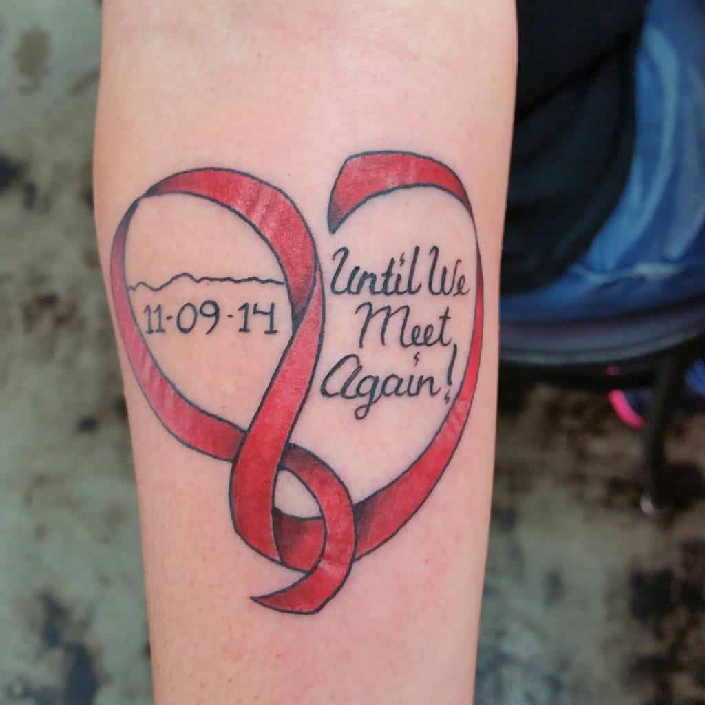 Red heart ribbon tattoo with "11-09-14" and "Until We Meet Again!" intertwined in an infinity symbol on an arm