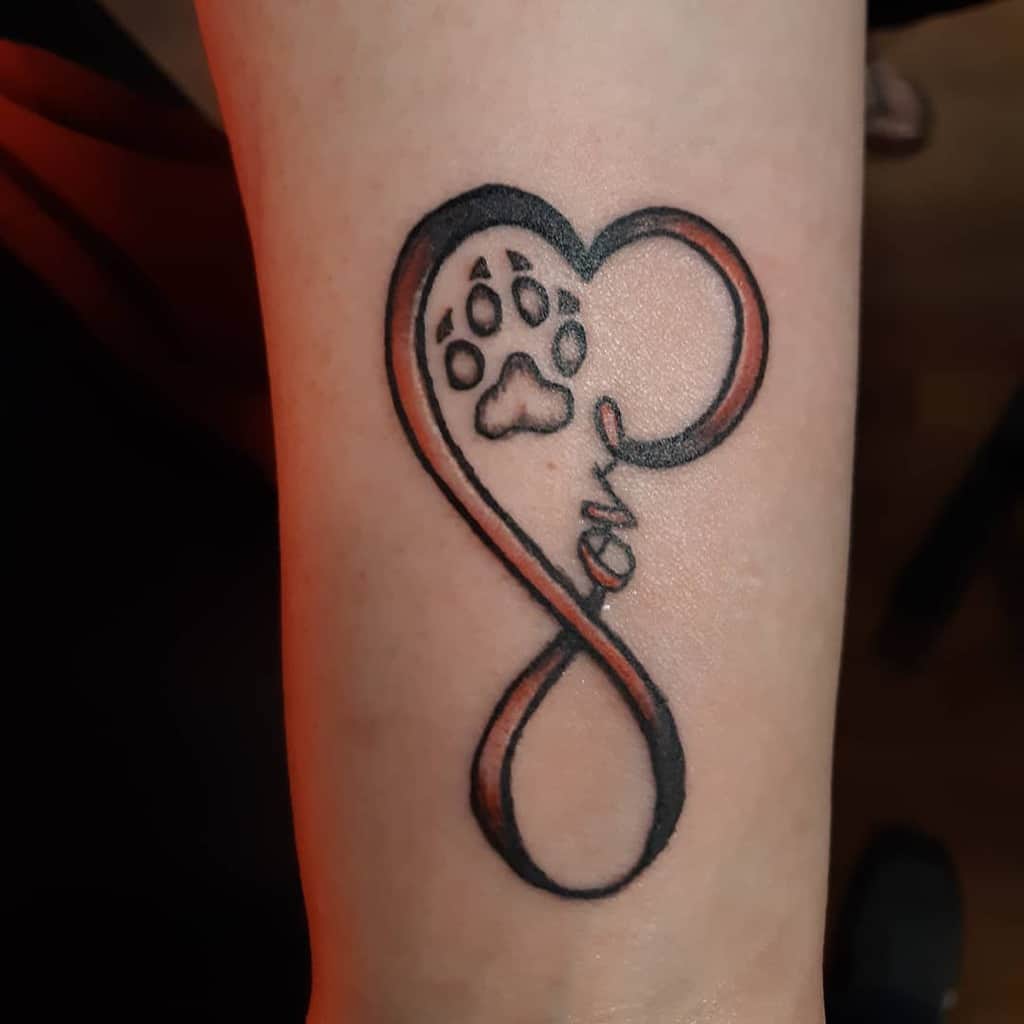 Infinity tattoo with a paw print and the word "love" intertwined with a heart on an arm