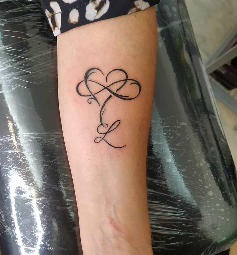 A tattoo of a heart and the intertwined initials "T" and "L," elegantly shaped like an infinity symbol
