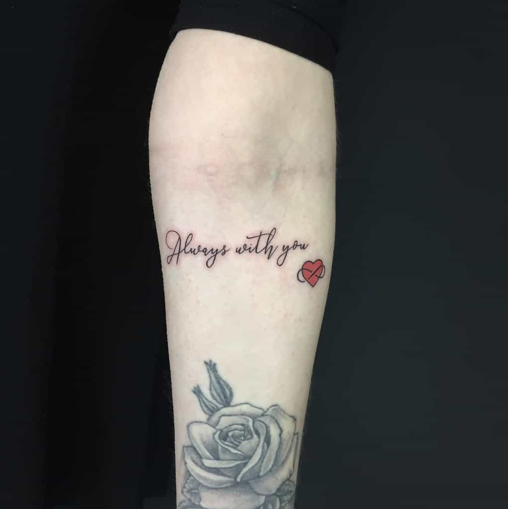 Forearm tattoo reading "Always with you" with a small red heart next to a rose tattoo