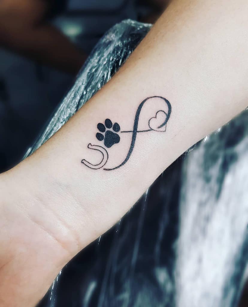 Tattoo on an arm featuring a paw print and a heart intertwined with an infinity symbol