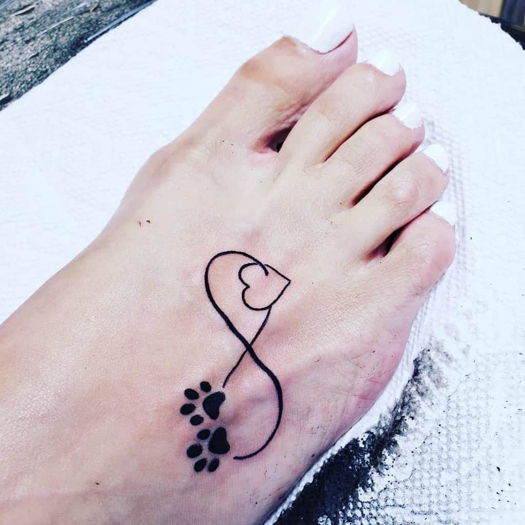 Foot tattoo featuring an infinity symbol intertwined with paw prints and a delicate heart design