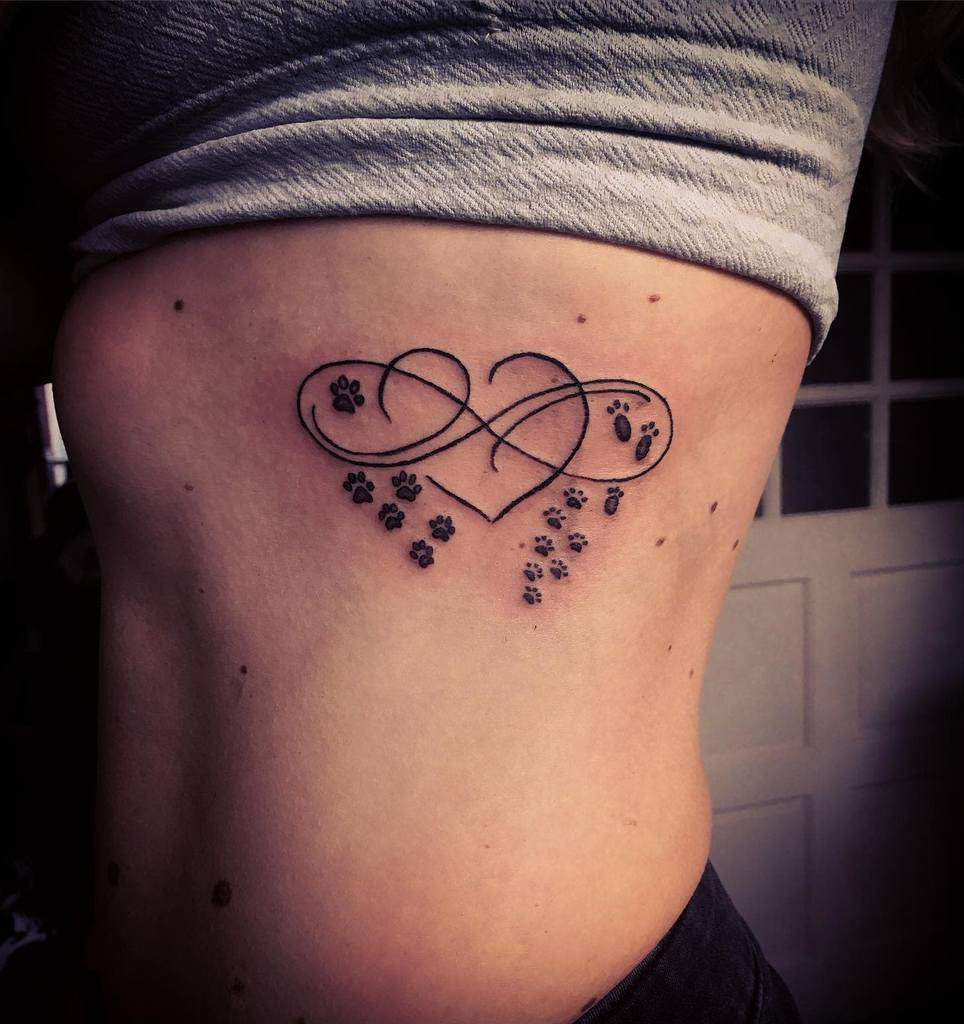 Tattoo of interlocking hearts and paw prints in an infinity design on a ribcage