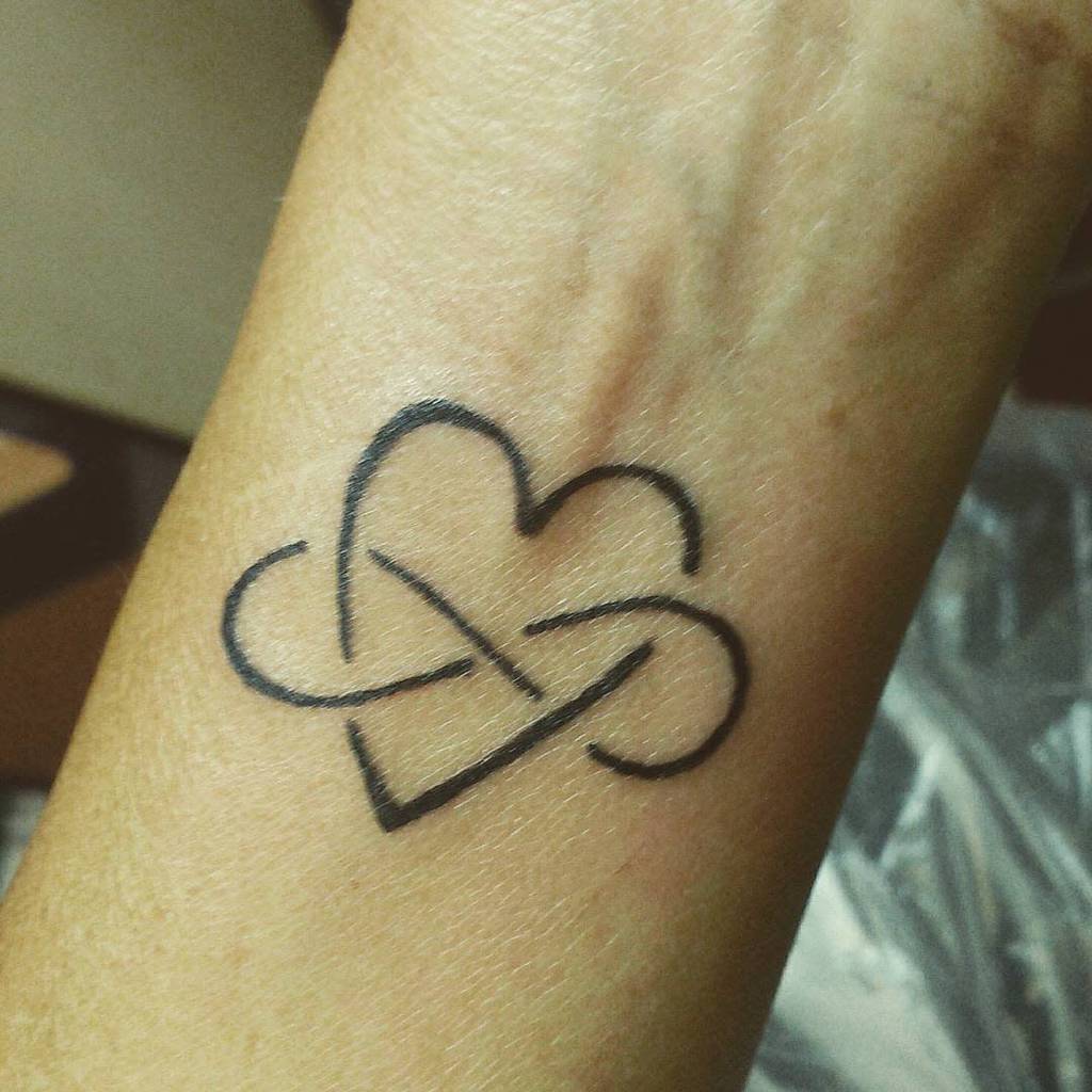 A tattoo of a heart intertwined with an infinity symbol on a wrist