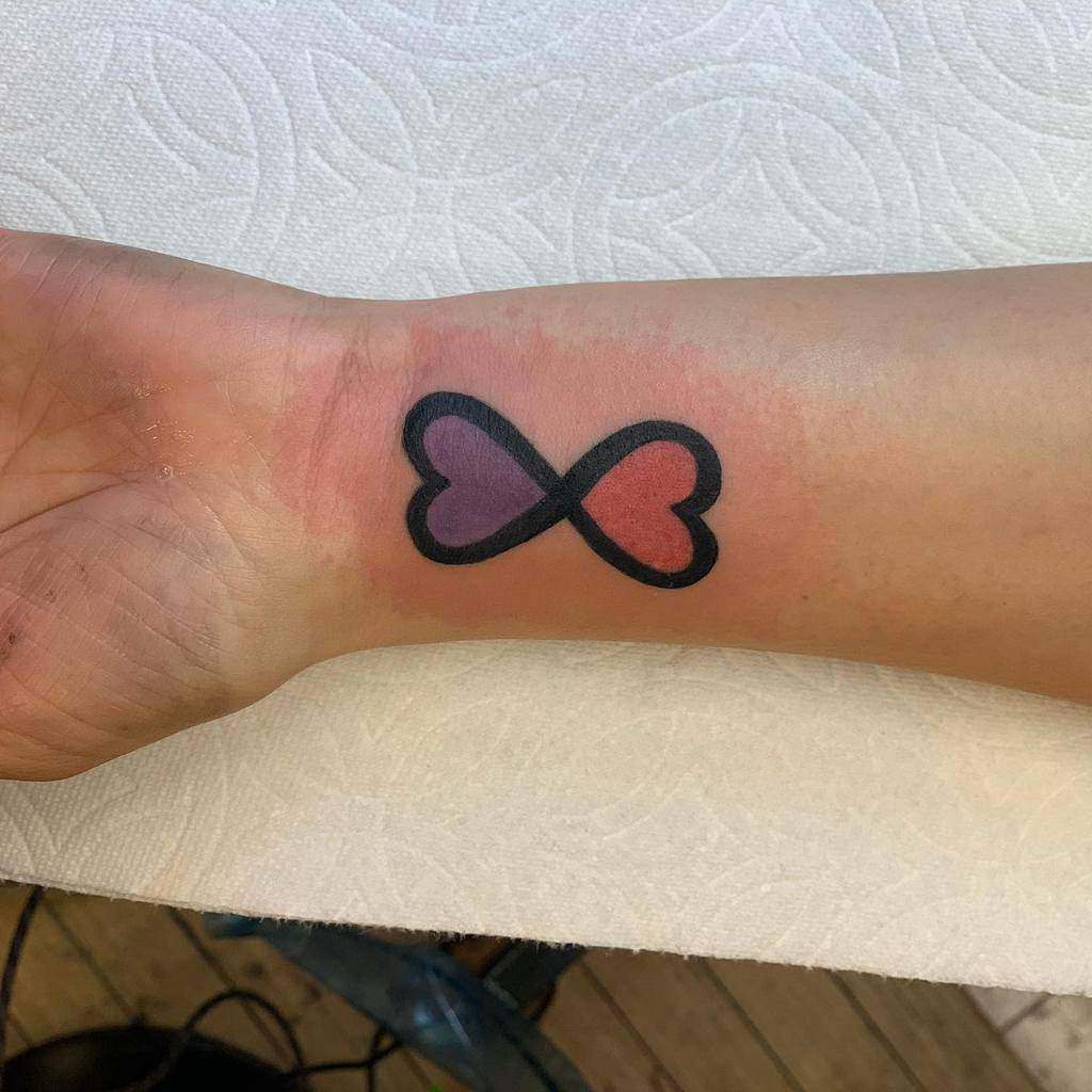 Tattoo of two hearts connected forming an infinity symbol: the left heart is purple, the right is red