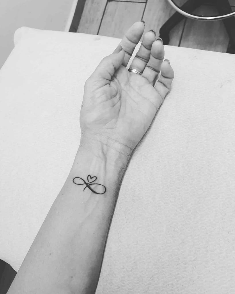 A tattoo of an infinity symbol with a heart on a wrist