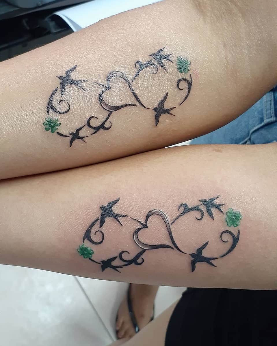 Matching heart and vine tattoos with green accents on forearms