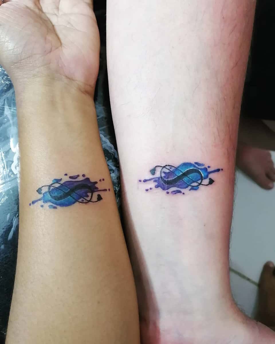 Matching blue and purple DNA helix tattoos on two forearms