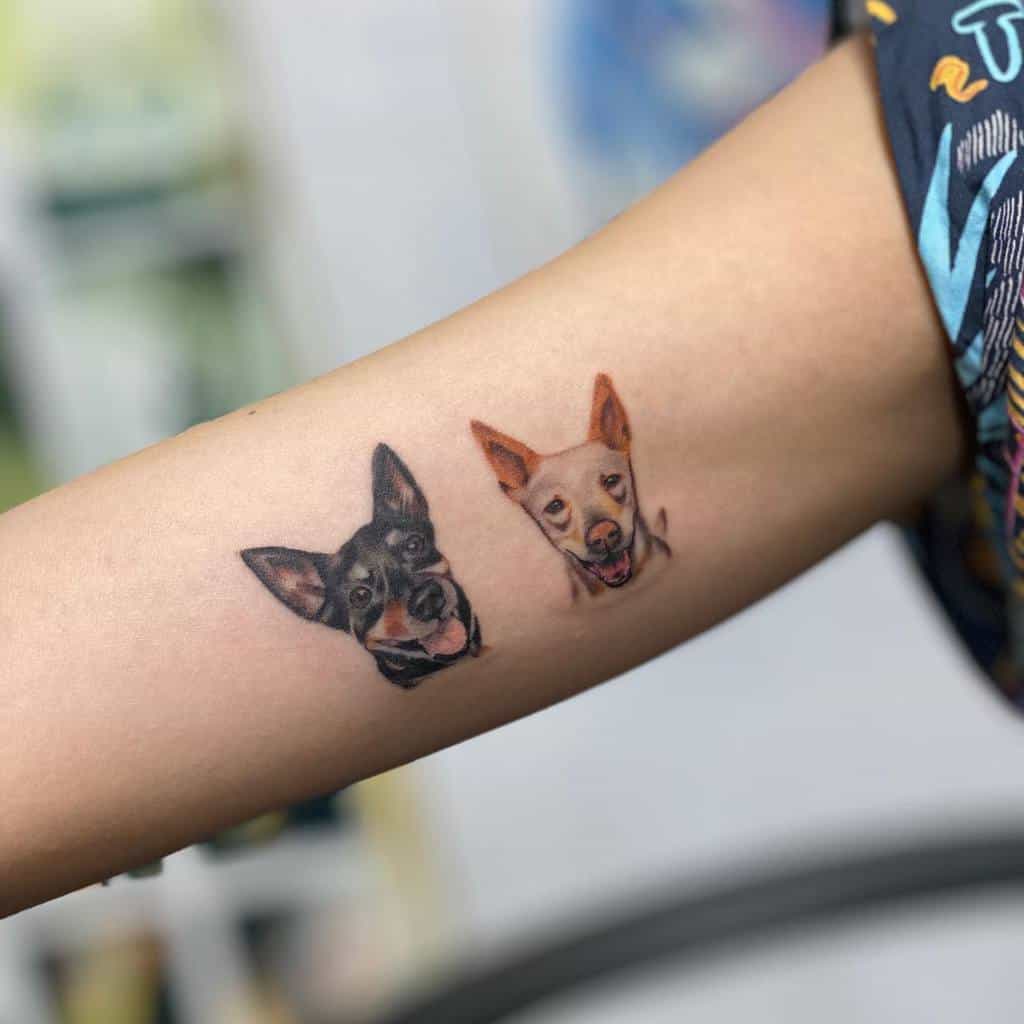 Realistic inner arm tattoo featuring two small, detailed portraits of dogs with expressive facial features