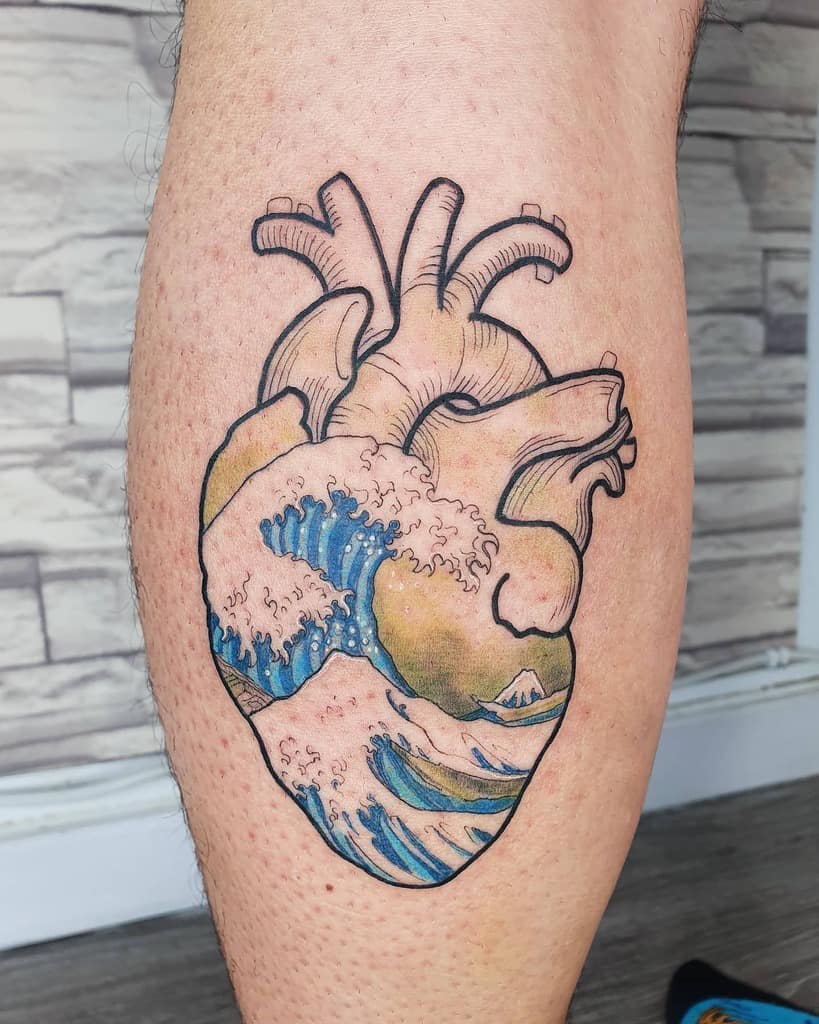 A colorful tattoo of an anatomical heart featuring ocean waves inspired by The Great Wave off Kanagawa