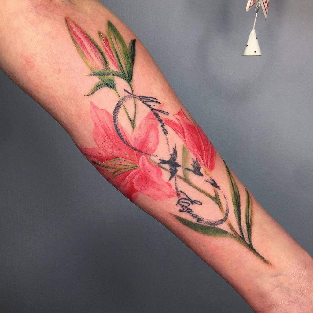 Elegant forearm tattoo featuring pink lilies, an infinity symbol, two birds, and cursive script reading 'Milana & Egor'