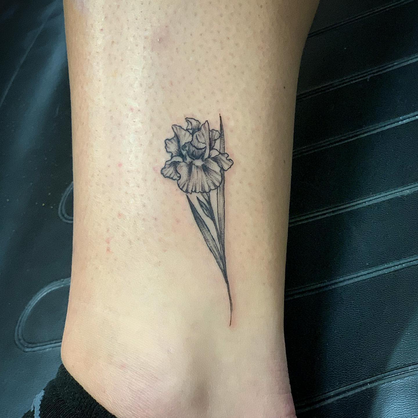 Simple monochrome iris tattoo on a leg