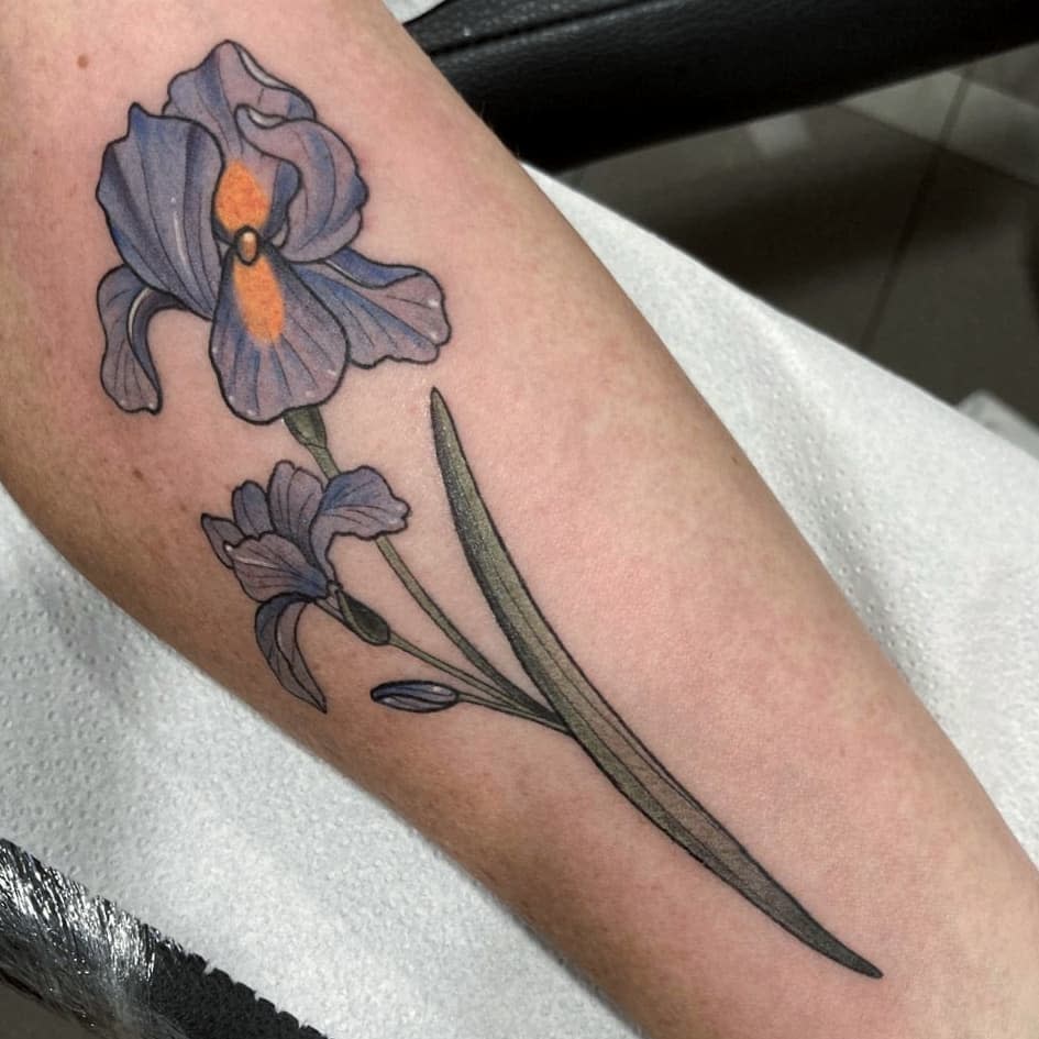 Tattoo of purple iris flower with green stem and leaves on a forearm