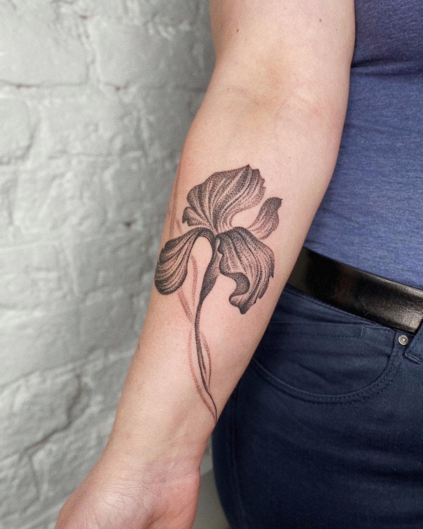 A black iris tattoo on a forearm