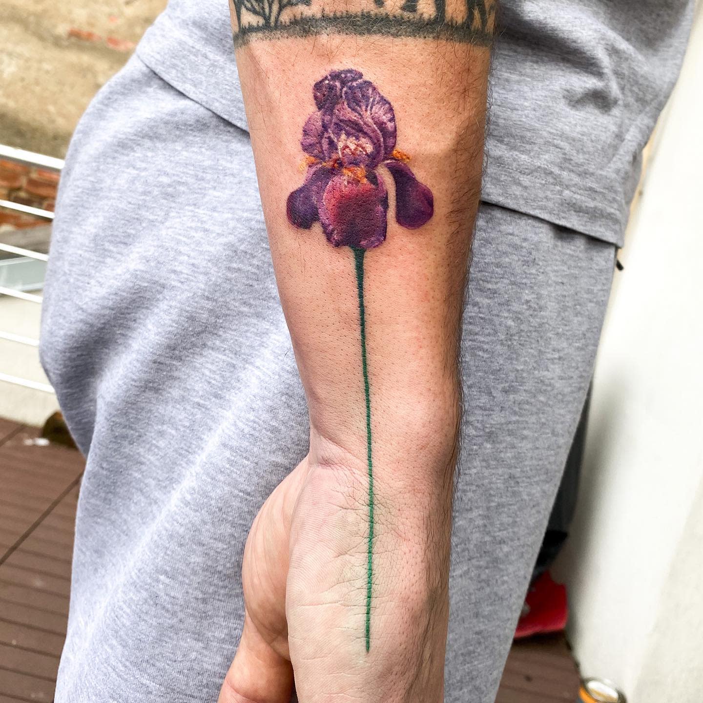 Tattoo of a purple iris flower on a forearm