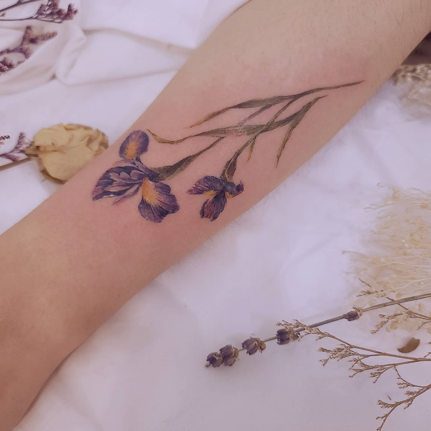 Arm with a purple iris flower tattoo