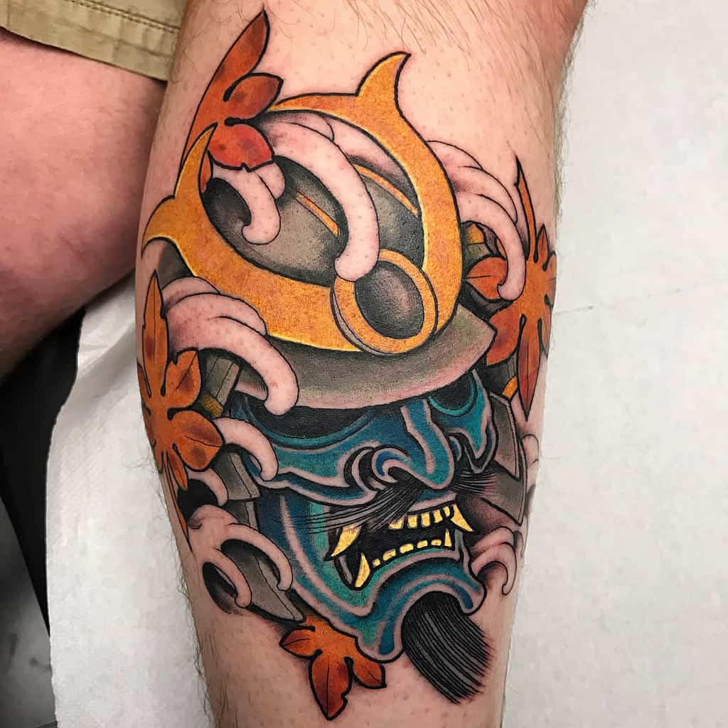 Colorful tattoo of a samurai mask, with dynamic swirling patterns, orange flowers, and intricate helmet details for a bold, vibrant look