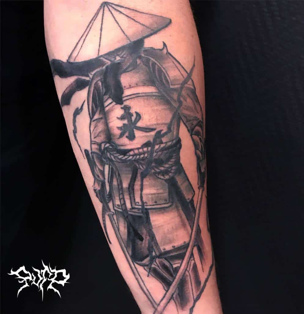 Tattoo of a ronin samurai in a hat, holding a sword, with Japanese kanji on the arm